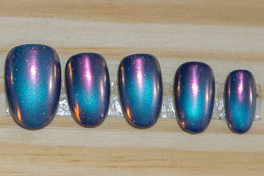 blue galaxy cateye with pink chrome overlay press on nails on a wooden background