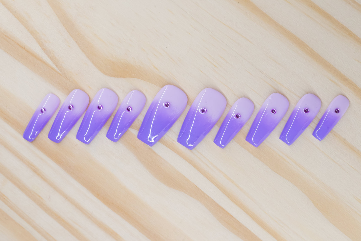 royal purple to lavender ombre press on nails with single rhinestone each featured on a wooden background