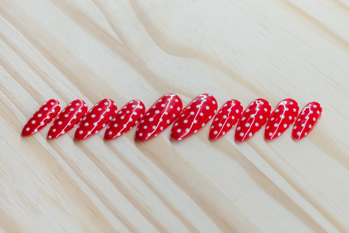 red press on nails with white polka dots on a wooden background