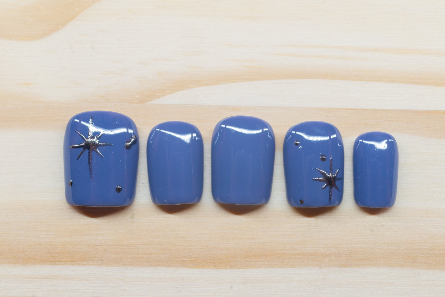 twilight blue press on nails with elegant silver chrome star motif featured on a wooden background