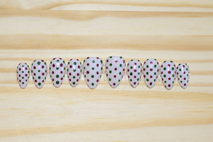 white press on nails with dark red and green polka dots on a wooden background