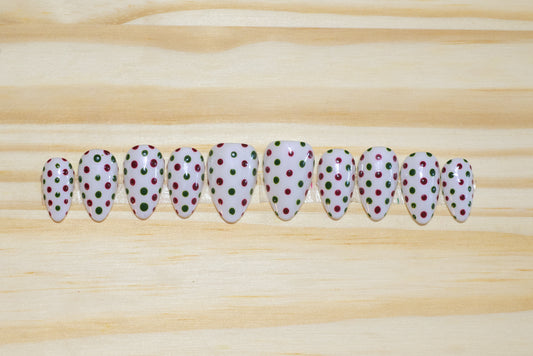 white press on nails with dark red and green polka dots on a wooden background