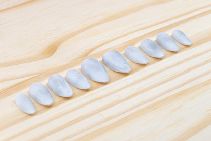 Icy white/silver cat eye press on nails that mimic the look of a frosty window, featured on a wooden background