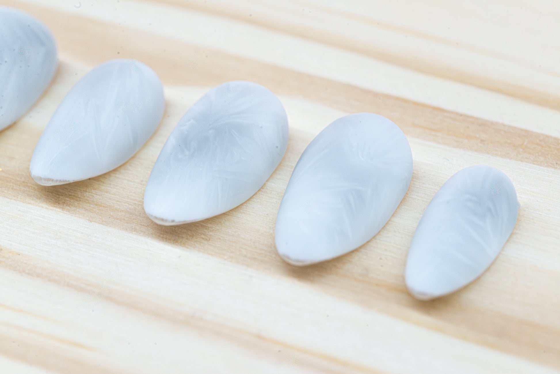 Icy white/silver cat eye press on nails that mimic the look of a frosty window, featured on a wooden background