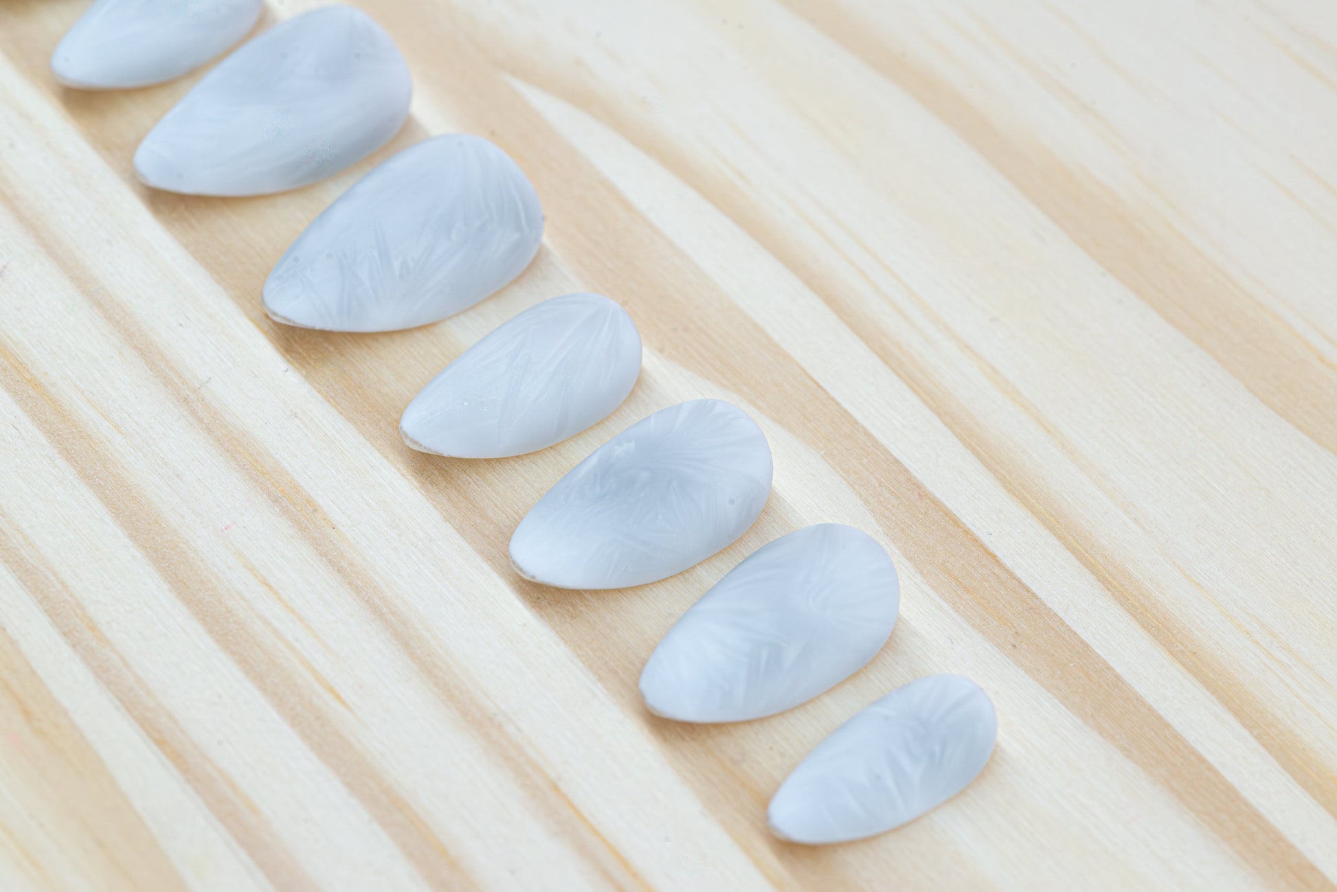 Icy white/silver cat eye press on nails that mimic the look of a frosty window, featured on a wooden background