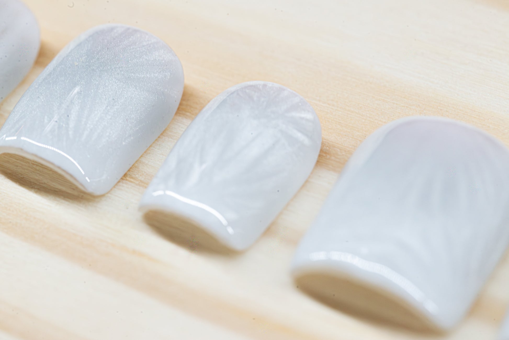 Icy white/silver cat eye press on nails that mimic the look of a frosty window, featured on a wooden background