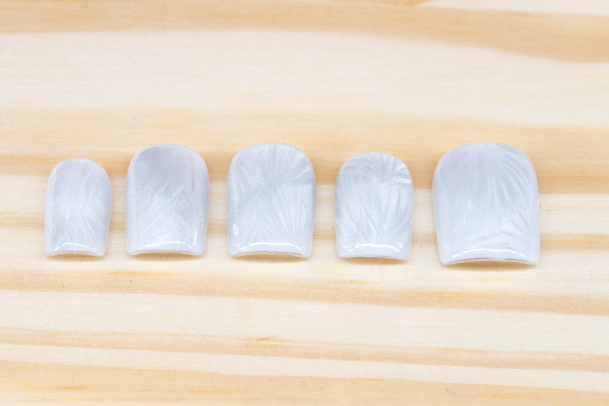 Icy white/silver cat eye press on nails that mimic the look of a frosty window, featured on a wooden background