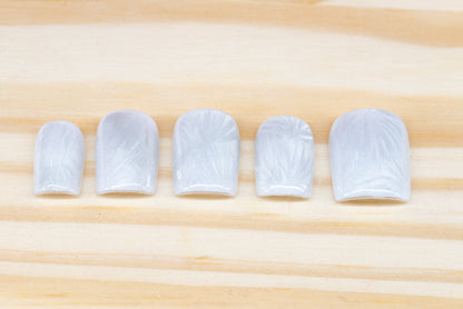 Icy white/silver cat eye press on nails that mimic the look of a frosty window, featured on a wooden background