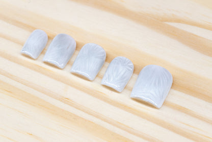 Icy white/silver cat eye press on nails that mimic the look of a frosty window, featured on a wooden background