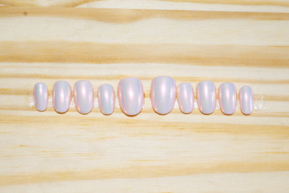 Pale pink press on nails with translucent pink/orange chrome glossy finish featured on a wooden background