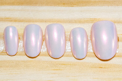 Pale pink press on nails with translucent pink/orange chrome glossy finish featured on a wooden background