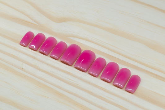 Berry pink aura-design press on nails featured on a wooden background