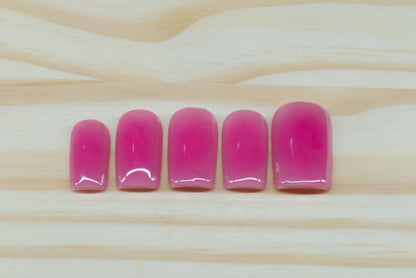 Berry pink aura-design press on nails featured on a wooden background