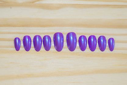 Purple press on nails with transparent blue chrome overlay featured on a wooden background