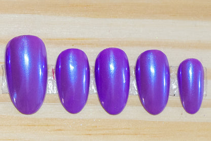 Purple press on nails with transparent blue chrome overlay featured on a wooden background