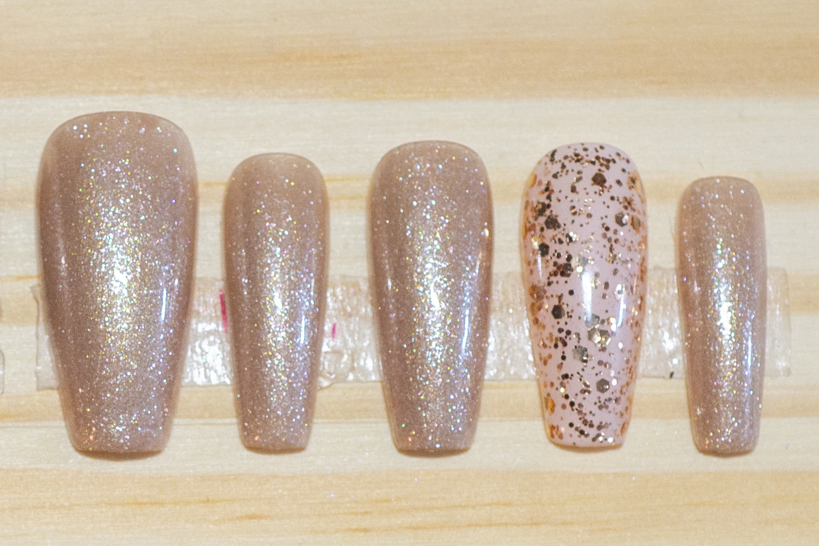 Shimmery champagne gold press on nails with glittery gold accent nails featured on a wooden background