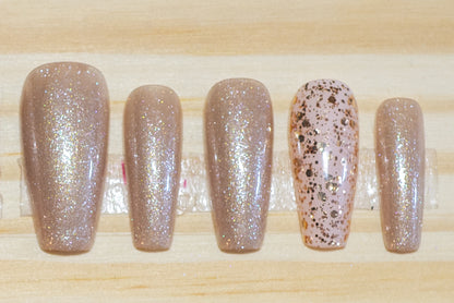 Shimmery champagne gold press on nails with glittery gold accent nails featured on a wooden background