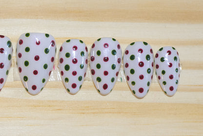 white press on nails with dark red and green polka dots on a wooden background