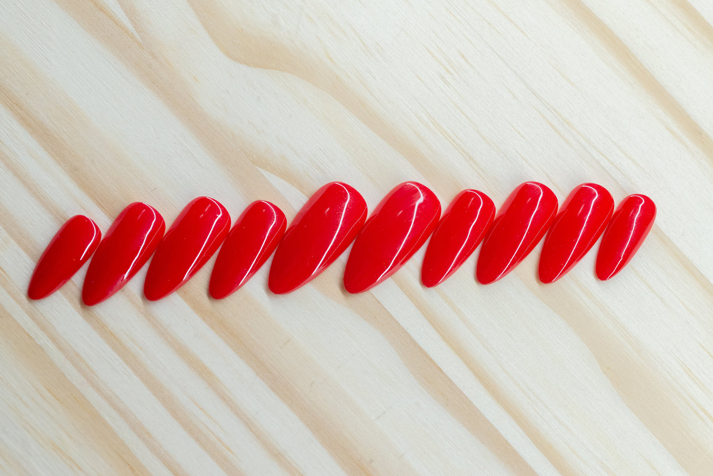 classic red press on nails featured on a wooden background