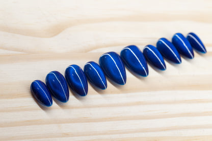 Deep blue cat eye effect press on nails featured on a wooden background