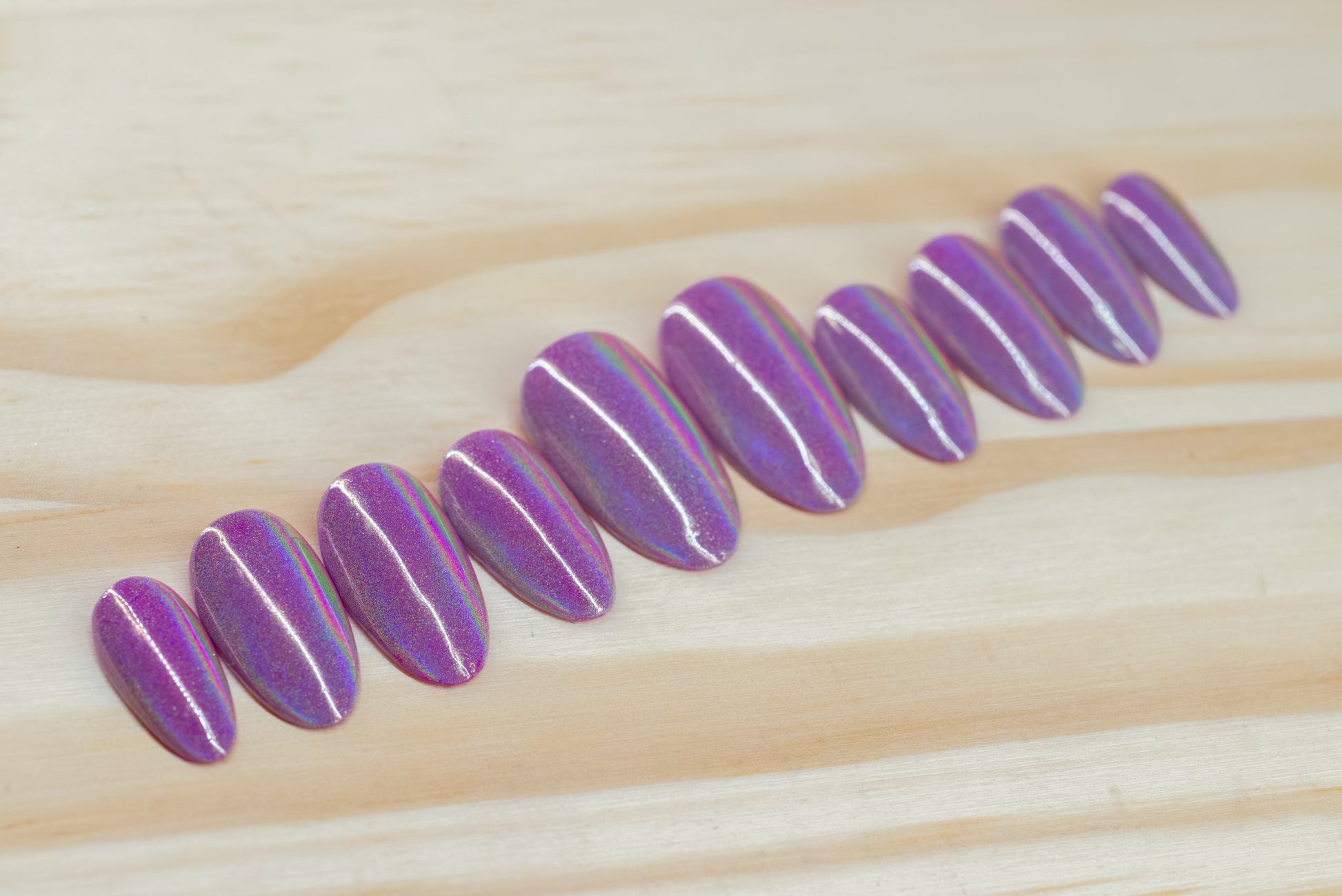 violet purple press on nails with holographic overlay featured on a wooden background