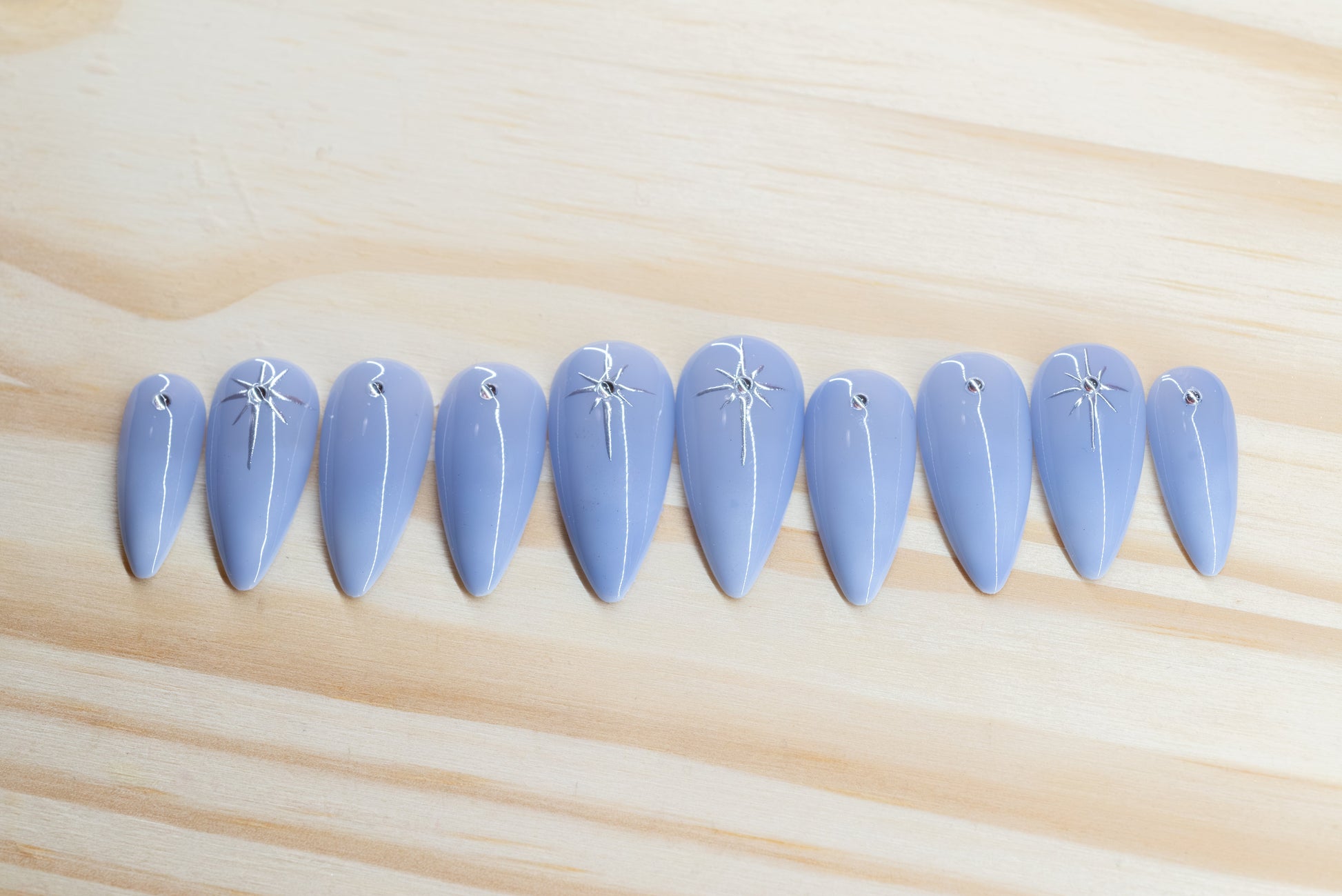 delicate light purple ombre press on nails with rhinestone/star detail featured on a wooden background