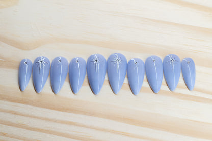 delicate light purple ombre press on nails with rhinestone/star detail featured on a wooden background