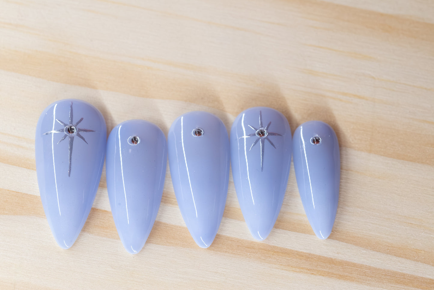 delicate light purple ombre press on nails with rhinestone/star detail featured on a wooden background