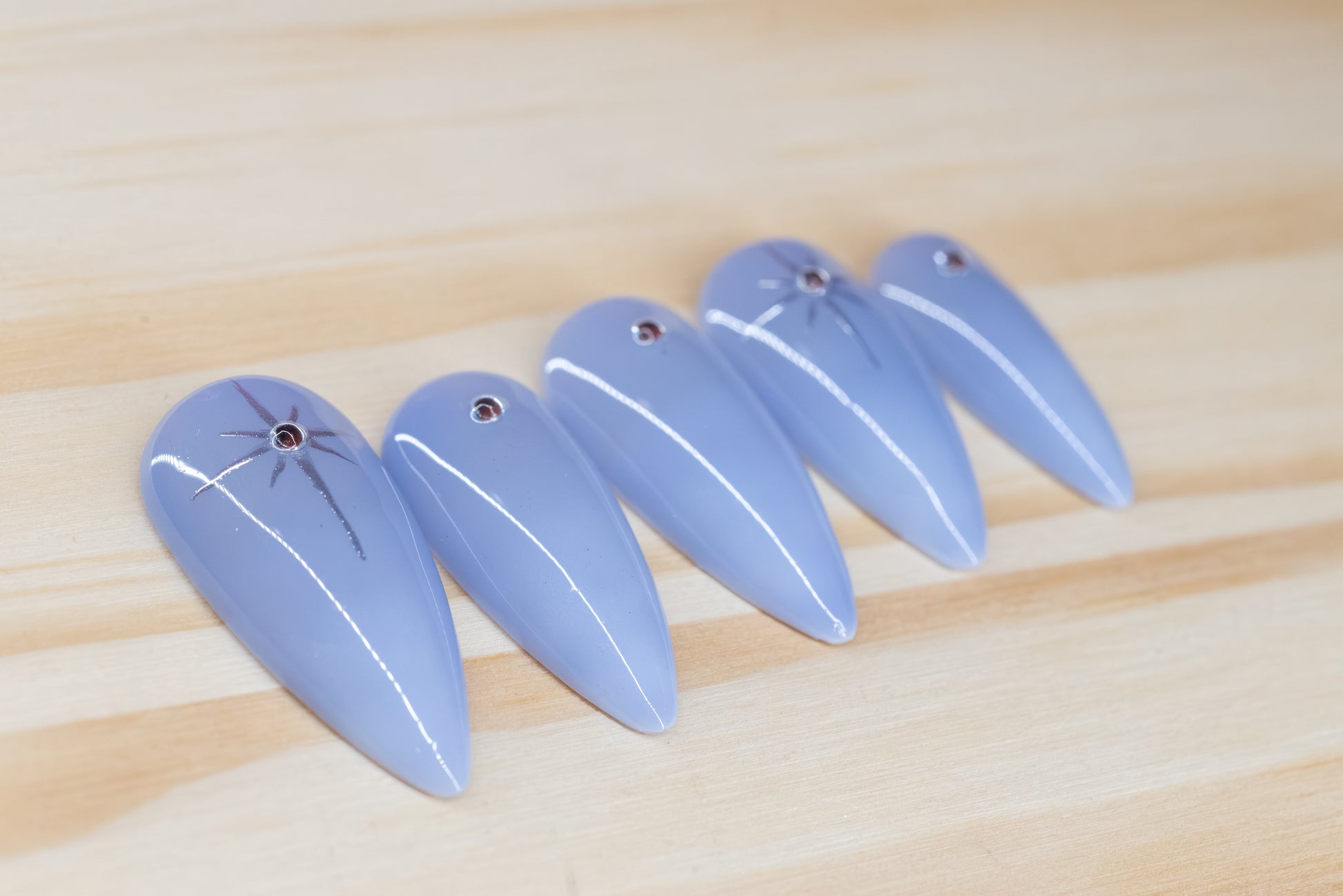 delicate light purple ombre press on nails with rhinestone/star detail featured on a wooden background