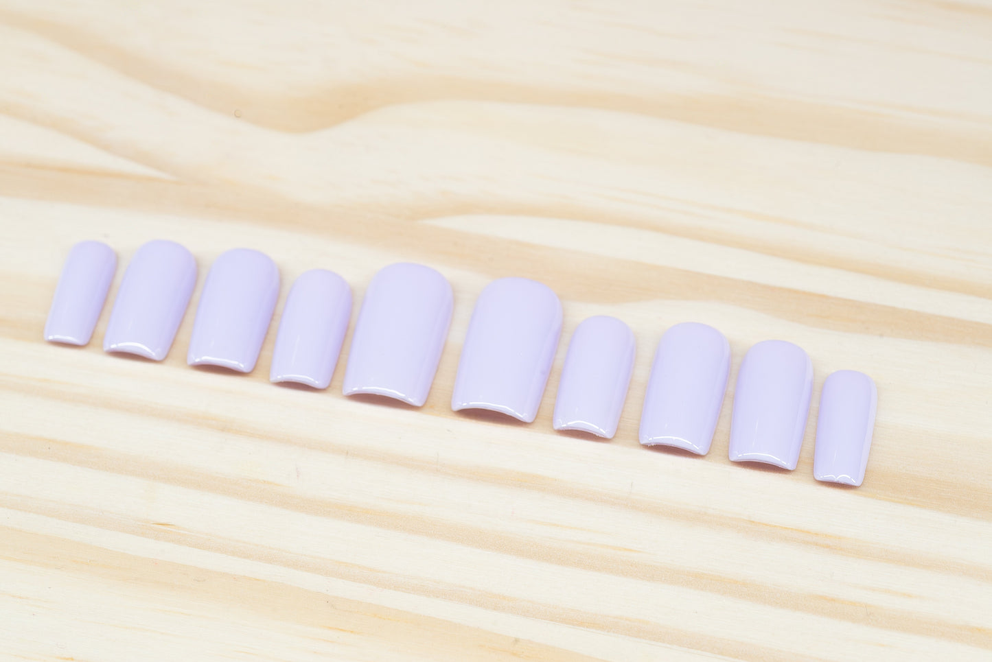 Set of pale lilac press on nails featured on a wooden background