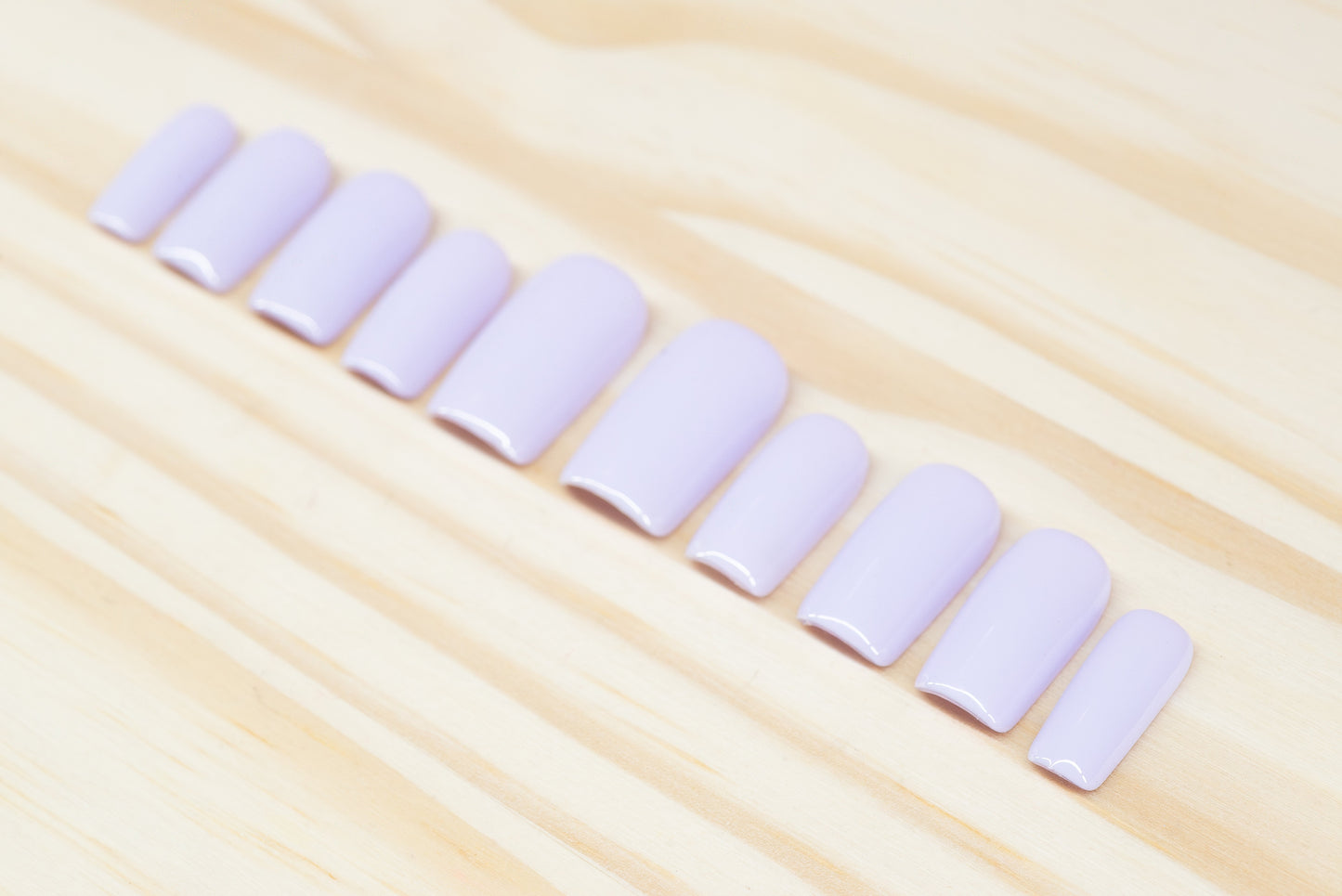 Set of pale lilac press on nails featured on a wooden background