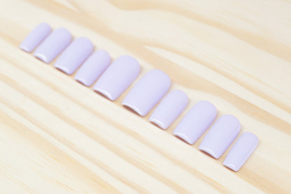 Set of pale lilac press on nails featured on a wooden background