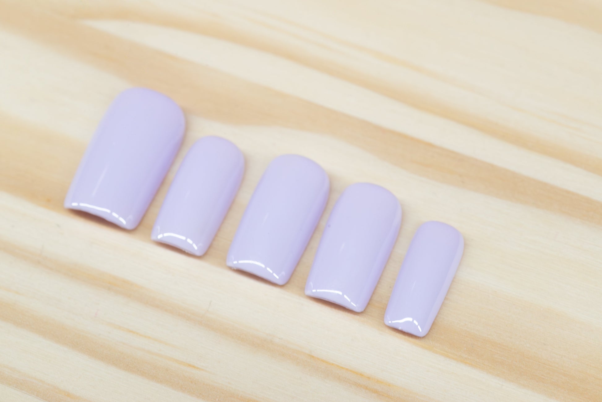 Set of pale lilac press on nails featured on a wooden background