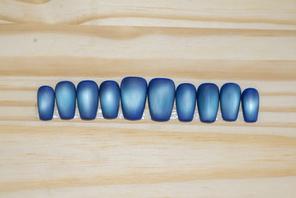 Deep blue with pale blue flash cat eye press on nails on a wooden background