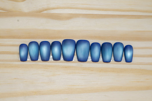 Deep blue with pale blue flash cat eye press on nails on a wooden background