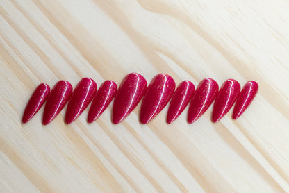 Sparkly berry pink press on nails featured on a wooden background