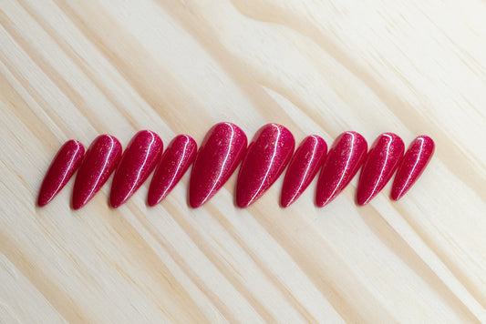 Sparkly berry pink press on nails featured on a wooden background