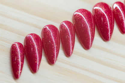 Sparkly berry pink press on nails featured on a wooden background