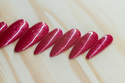 Sparkly berry pink press on nails featured on a wooden background