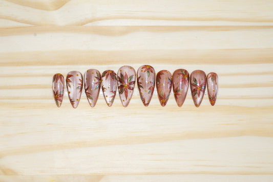 Hand-painted press on nails with chromed poinsettias on a neutral cateye base, featured on a wooden background