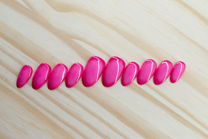 Deep pink press on nails with lighter pink aura design featured on a wooden background
