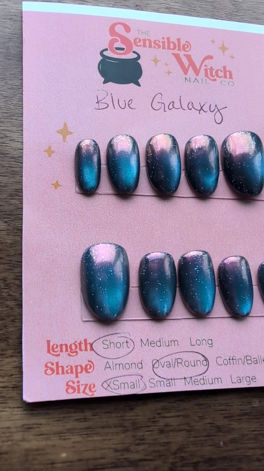 Video of set of blue galaxy cateye press on nails on a card with pink background