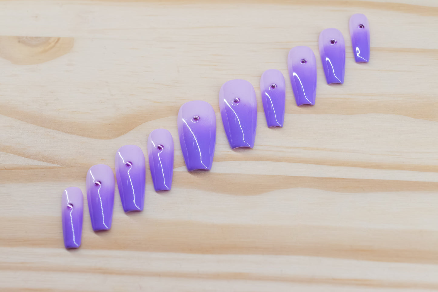 royal purple to lavender ombre press on nails with single rhinestone each featured on a wooden background