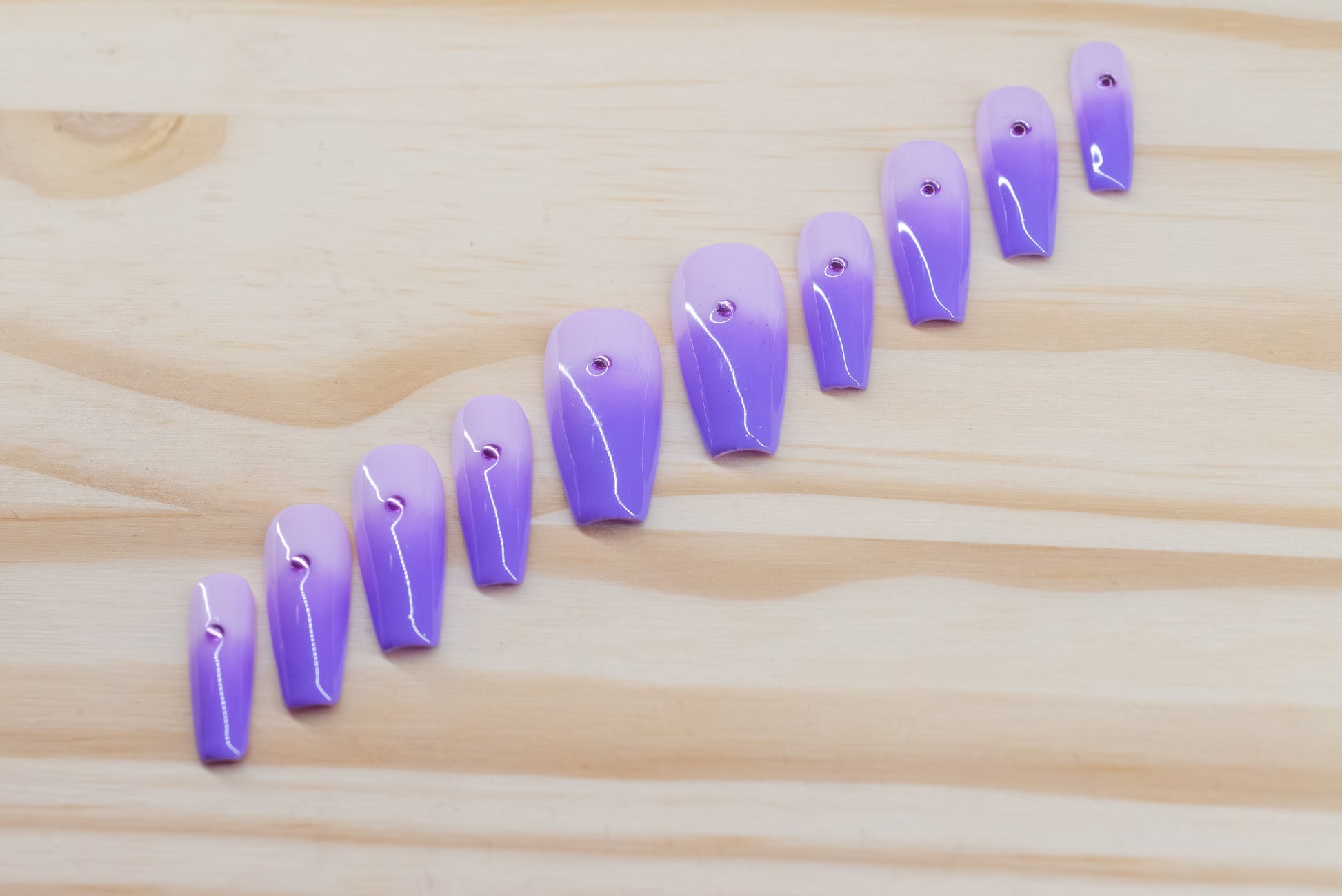royal purple to lavender ombre press on nails with single rhinestone each featured on a wooden background
