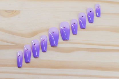 royal purple to lavender ombre press on nails with single rhinestone each featured on a wooden background