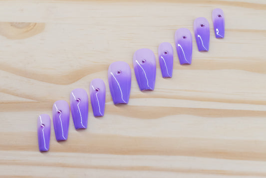 royal purple to lavender ombre press on nails with single rhinestone each featured on a wooden background