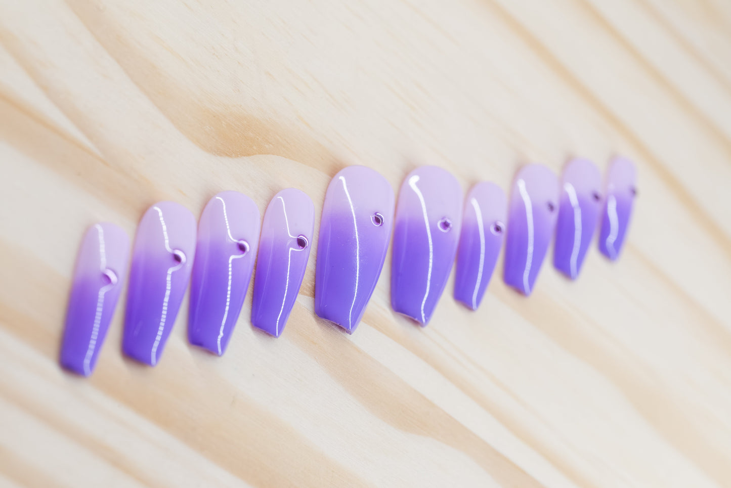 royal purple to lavender ombre press on nails with single rhinestone each featured on a wooden background