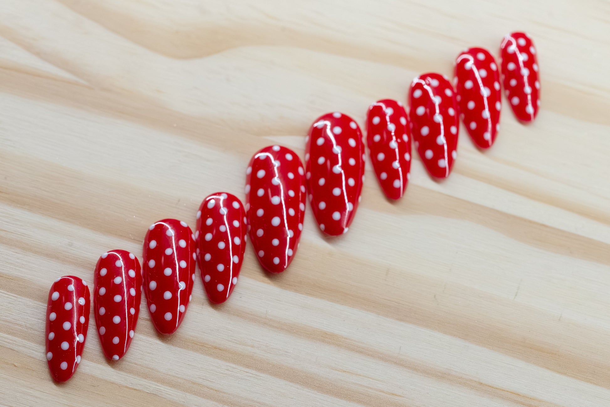 red press on nails with white polka dots on a wooden background