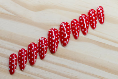 red press on nails with white polka dots on a wooden background