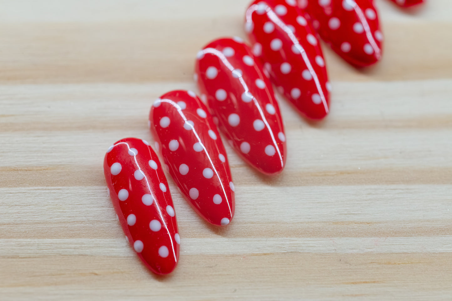 red press on nails with white polka dots on a wooden background